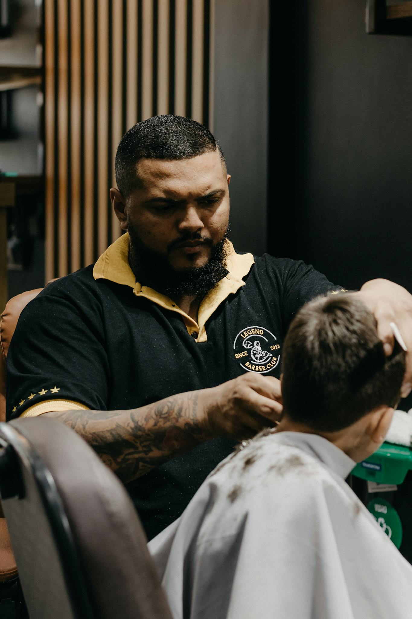 Barber expertly cutting a client's hair in a busy shop. Focus on professional grooming.