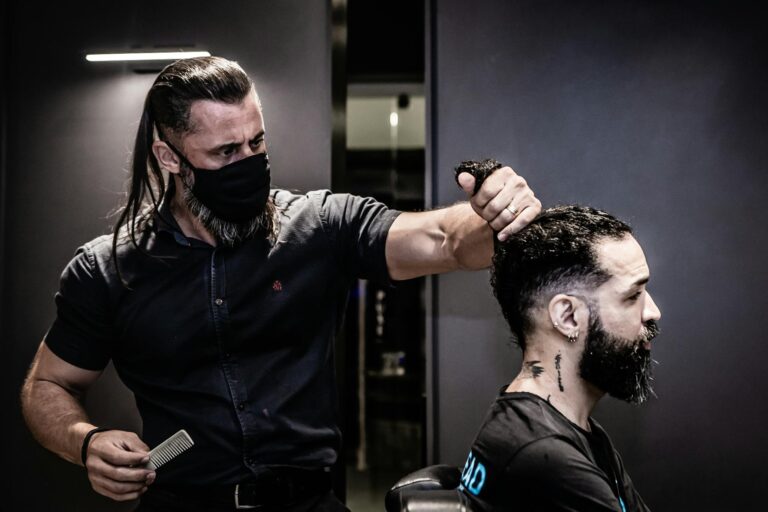 Barber in João Pessoa salon trims client's hair while wearing a face mask. Indoor setting.